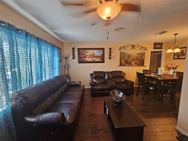 living room with a textured ceiling, wood-type flooring, and ceiling fan with notable chandelier