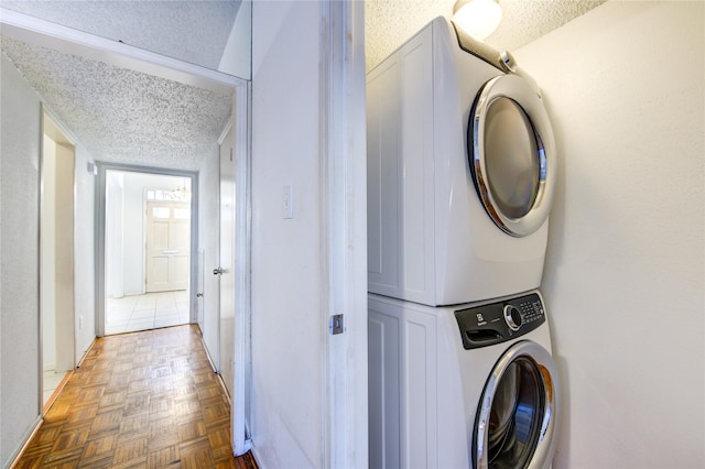 clothes washing area with stacked washer / dryer, parquet floors, and a textured ceiling