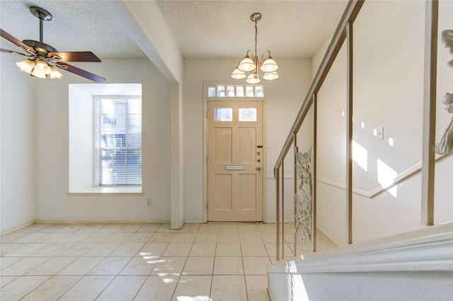 foyer entrance featuring ceiling fan with notable chandelier, light tile patterned floors, and a textured ceiling