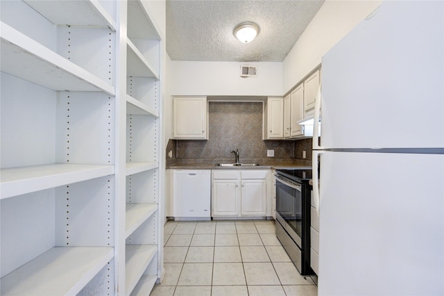 kitchen featuring sink, a textured ceiling, white appliances, decorative backsplash, and light tile patterned floors