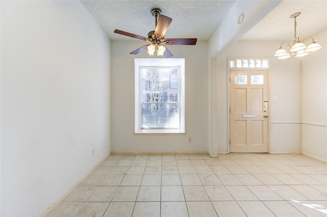 interior space with ceiling fan with notable chandelier, light tile patterned floors, and a textured ceiling