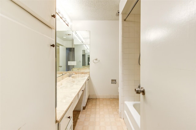 bathroom with vanity, a textured ceiling, and tiled shower / bath combo