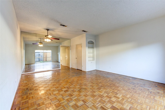 empty room with ceiling fan, a textured ceiling, and light parquet floors