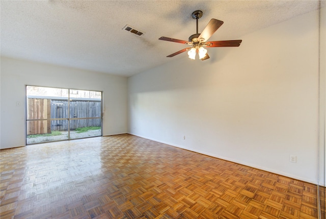 empty room with parquet floors, a textured ceiling, and ceiling fan