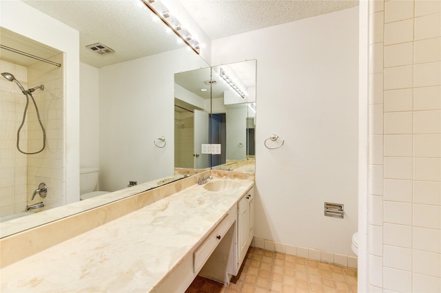 bathroom with vanity, toilet, and a textured ceiling