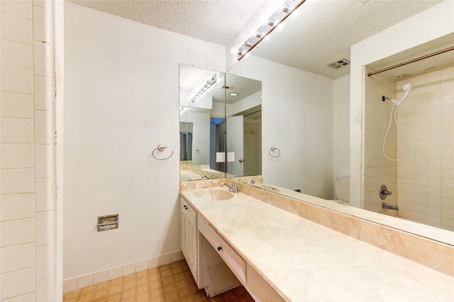 bathroom featuring vanity, a textured ceiling, and tiled shower / bath combo