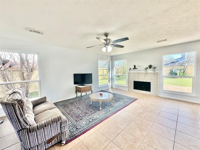 living room with a tile fireplace, light tile patterned floors, and a textured ceiling