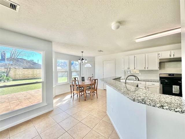 kitchen featuring tasteful backsplash, stainless steel range oven, a notable chandelier, decorative light fixtures, and white cabinets