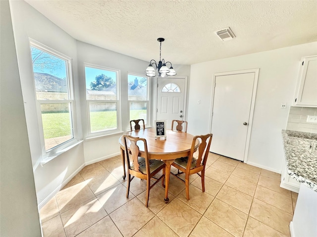 dining space with light tile patterned flooring, a textured ceiling, and an inviting chandelier