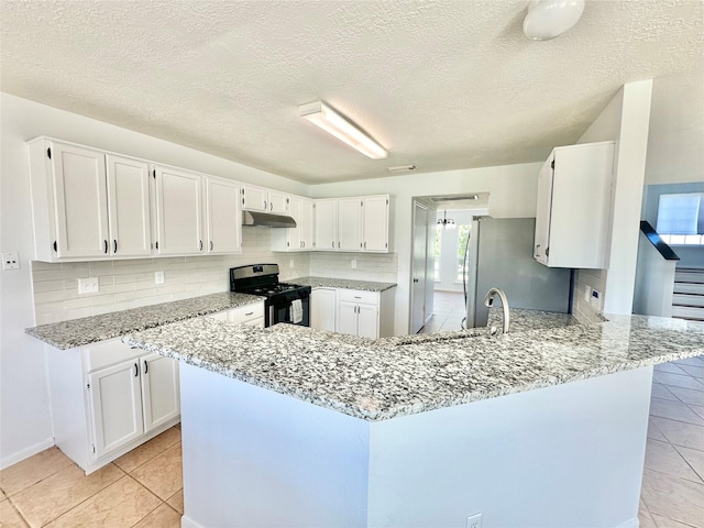 kitchen with kitchen peninsula, appliances with stainless steel finishes, white cabinets, and light stone countertops