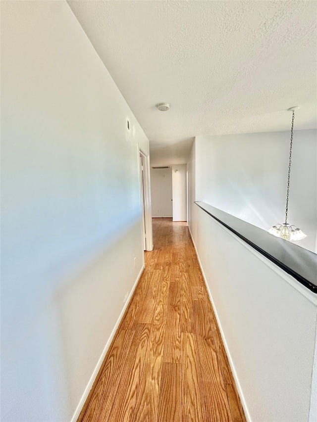 corridor featuring light wood-type flooring and a textured ceiling