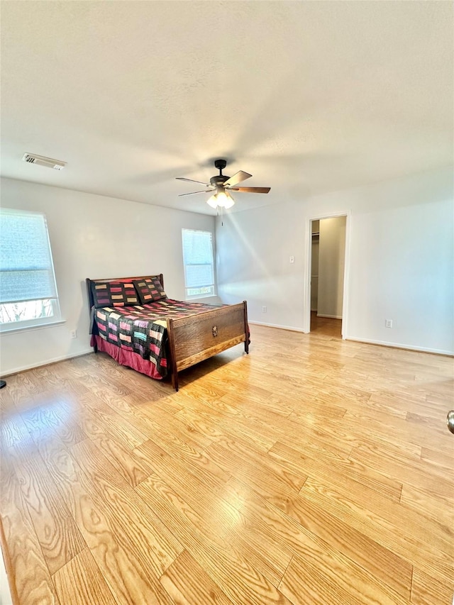 bedroom featuring multiple windows, ceiling fan, and light wood-type flooring