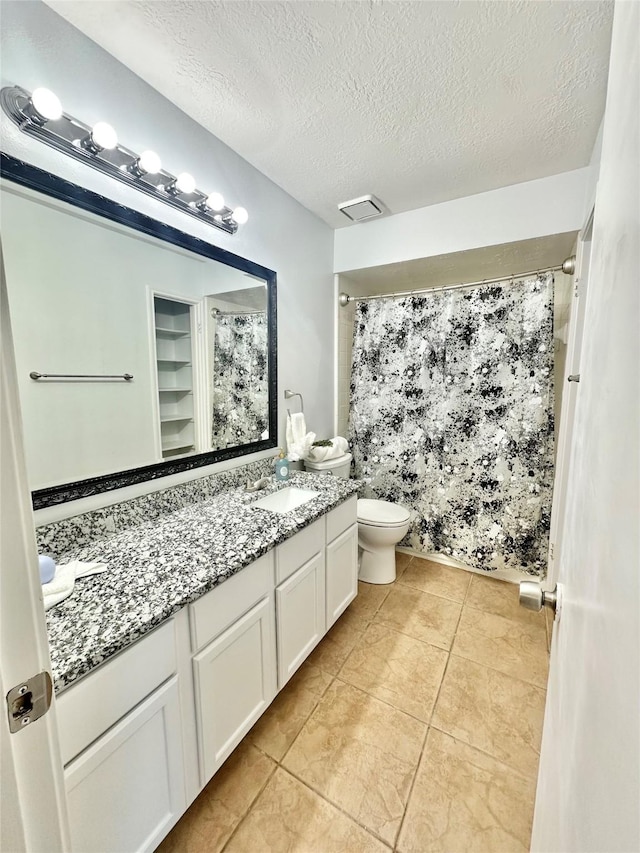 bathroom with vanity, a textured ceiling, toilet, and walk in shower