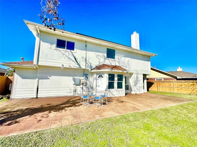 back of house with a lawn and a patio