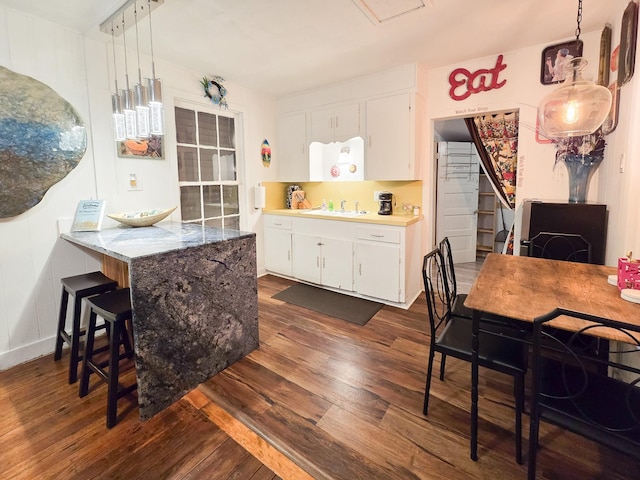 kitchen with sink, hanging light fixtures, dark hardwood / wood-style flooring, kitchen peninsula, and white cabinets