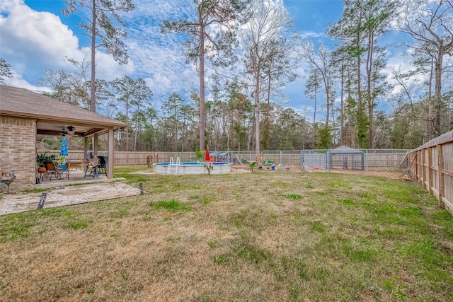 view of yard with a fenced in pool, a patio area, and ceiling fan