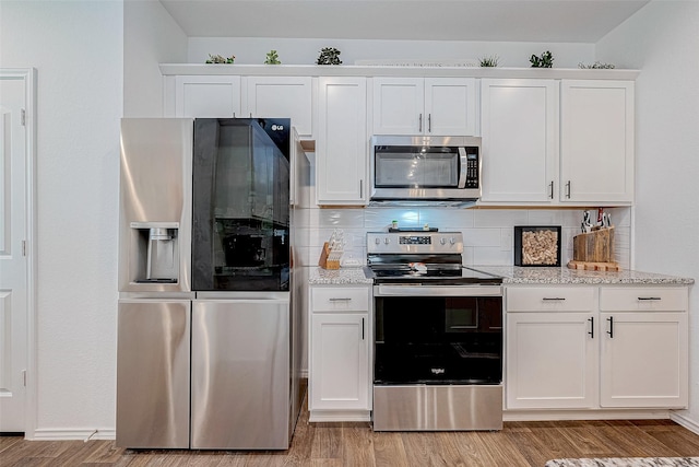 kitchen with light stone counters, white cabinets, stainless steel appliances, and tasteful backsplash