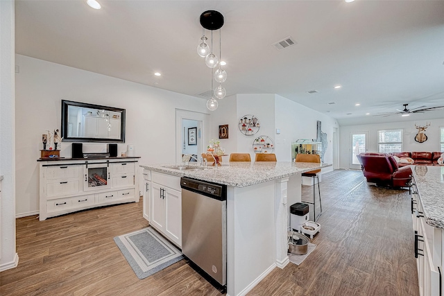 kitchen with dishwasher, pendant lighting, a kitchen breakfast bar, an island with sink, and white cabinets