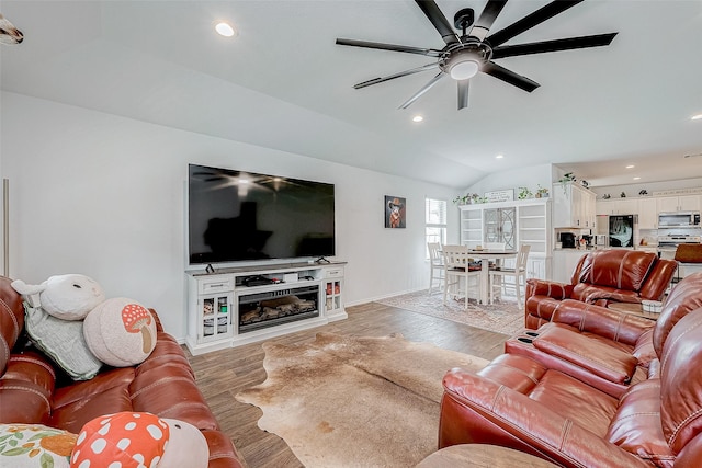 living room with ceiling fan, lofted ceiling, and hardwood / wood-style floors