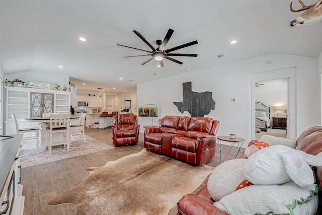 living room with light wood-type flooring, ceiling fan, and vaulted ceiling