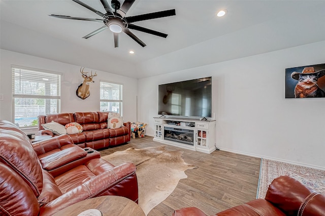 living room featuring ceiling fan, lofted ceiling, and light hardwood / wood-style flooring