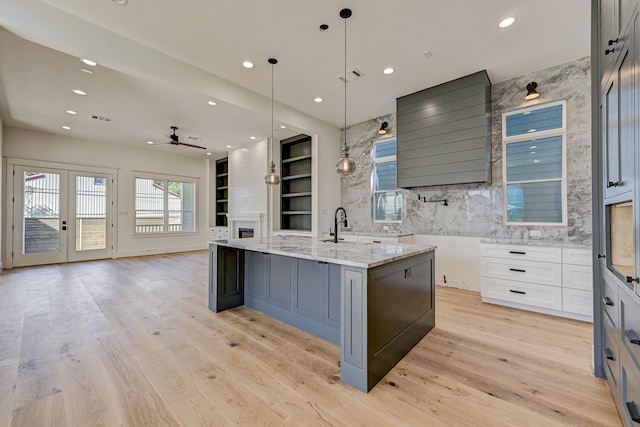 kitchen featuring light stone countertops, ceiling fan, white cabinetry, hanging light fixtures, and a large island