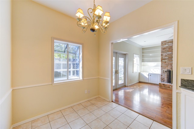 interior space featuring french doors, a brick fireplace, a chandelier, and a healthy amount of sunlight