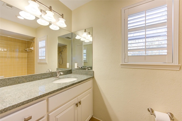 bathroom featuring a tile shower, a wealth of natural light, and vanity