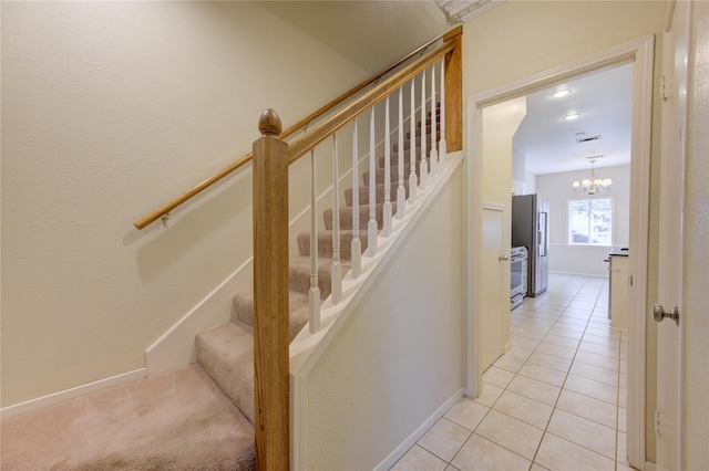 staircase with tile patterned floors and a notable chandelier