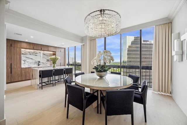 dining room featuring crown molding, light hardwood / wood-style flooring, expansive windows, and an inviting chandelier