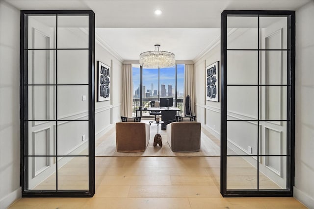 home office with light wood-type flooring, ornamental molding, and a chandelier