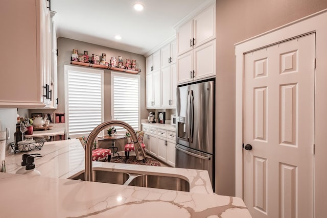 kitchen featuring light stone countertops, stainless steel fridge with ice dispenser, white cabinetry, and sink