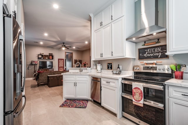 kitchen with white cabinets, wall chimney range hood, sink, kitchen peninsula, and stainless steel appliances