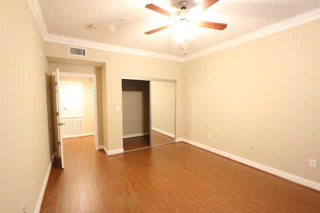 unfurnished bedroom with hardwood / wood-style flooring, ceiling fan, crown molding, and a closet