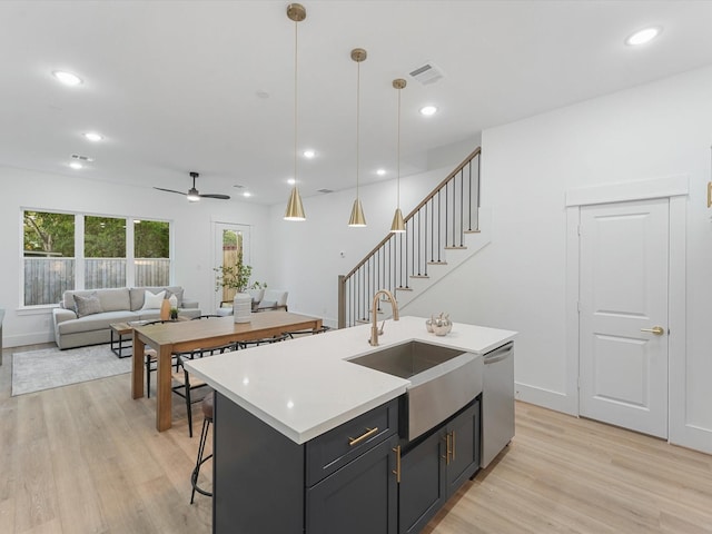 kitchen with ceiling fan, dishwasher, sink, hanging light fixtures, and a center island with sink