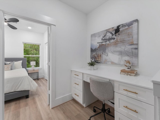 home office with light wood-type flooring, ceiling fan, and built in desk