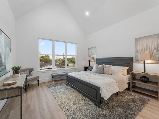 bedroom with light hardwood / wood-style floors and high vaulted ceiling