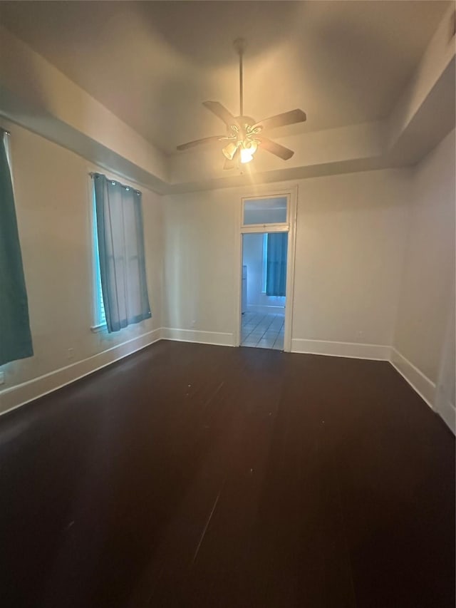 spare room with a raised ceiling, hardwood / wood-style flooring, and ceiling fan