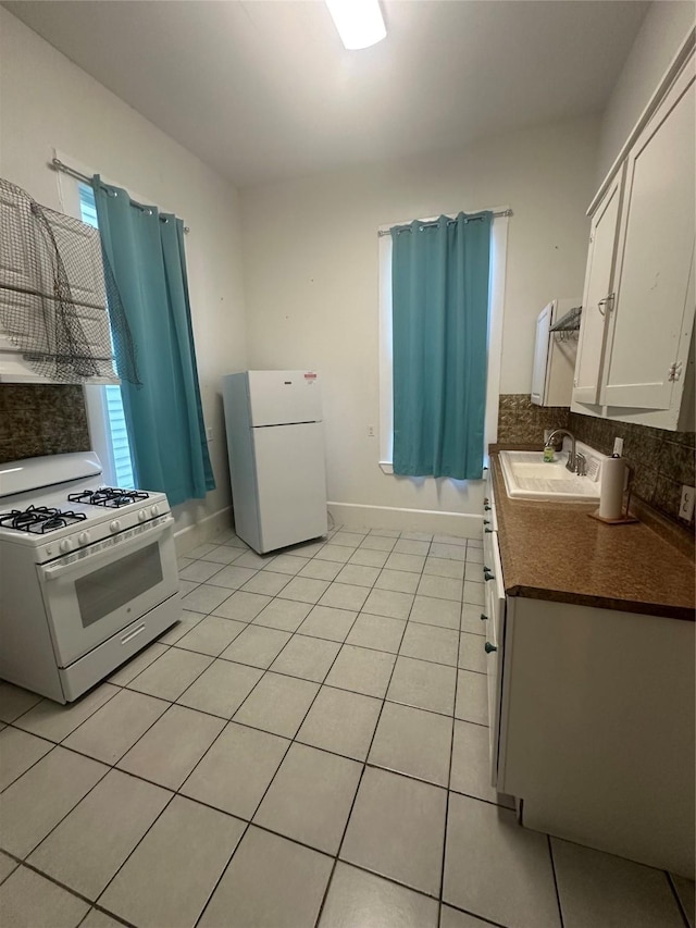 kitchen with light tile patterned flooring, sink, white cabinetry, white appliances, and decorative backsplash