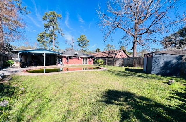 view of yard with a carport, a shed, a fenced backyard, and an outbuilding