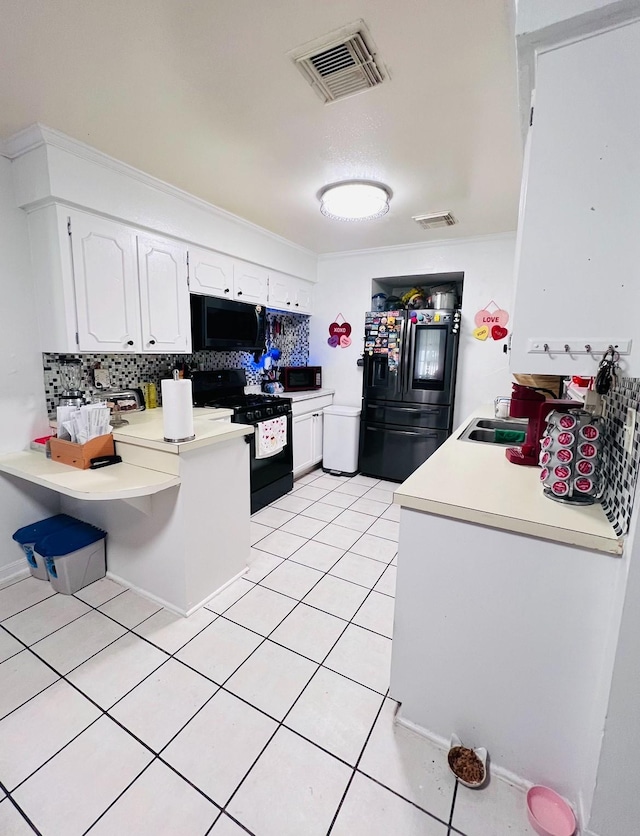 kitchen with light countertops, visible vents, backsplash, white cabinetry, and black appliances