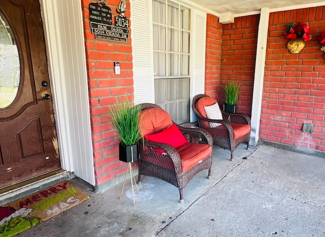 doorway to property with a porch and brick siding