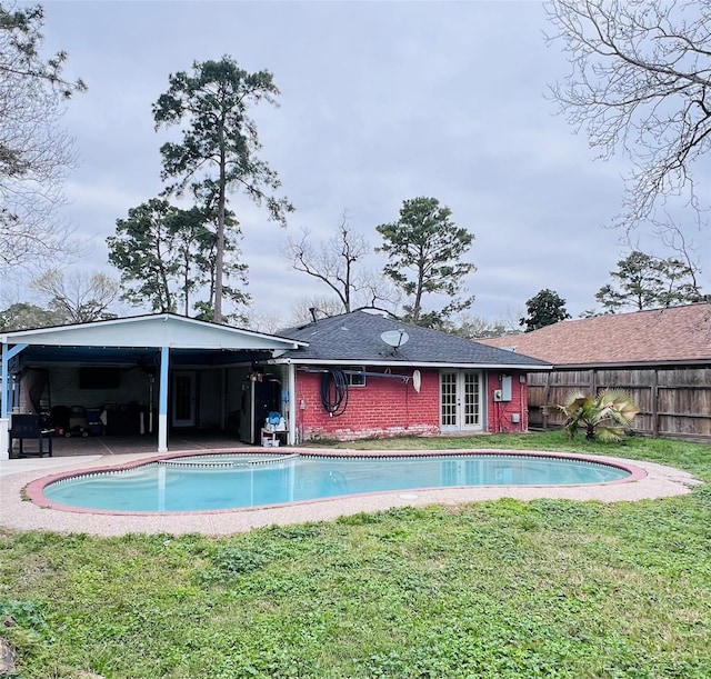 view of pool featuring a yard, fence, and french doors