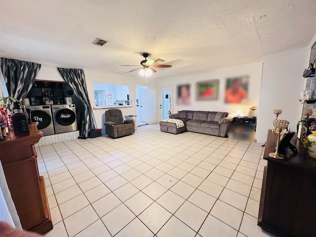 living area featuring visible vents, ceiling fan, a textured ceiling, washing machine and dryer, and light tile patterned flooring