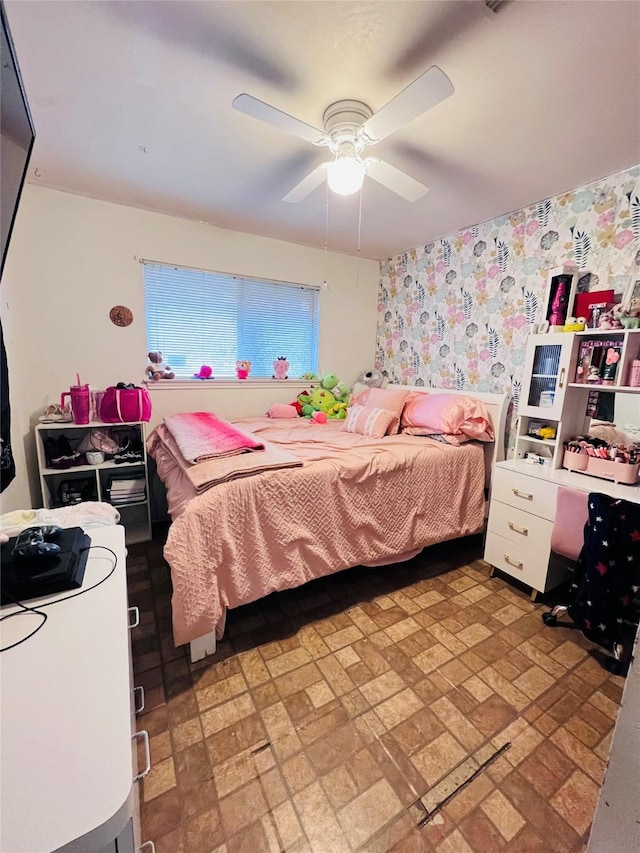 bedroom with a ceiling fan and wallpapered walls