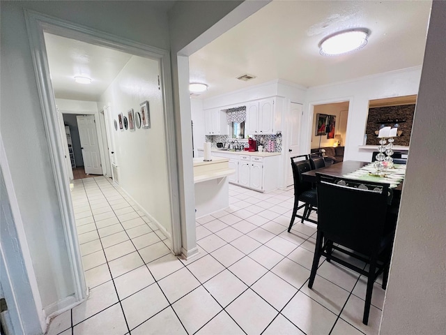 hall with light tile patterned flooring, visible vents, and baseboards