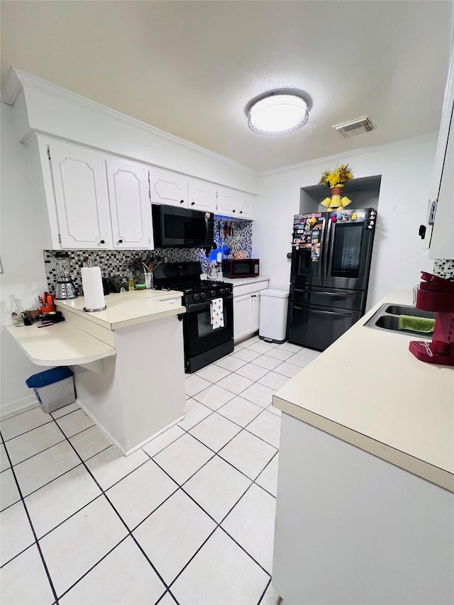 kitchen with white cabinets, black appliances, light countertops, and decorative backsplash