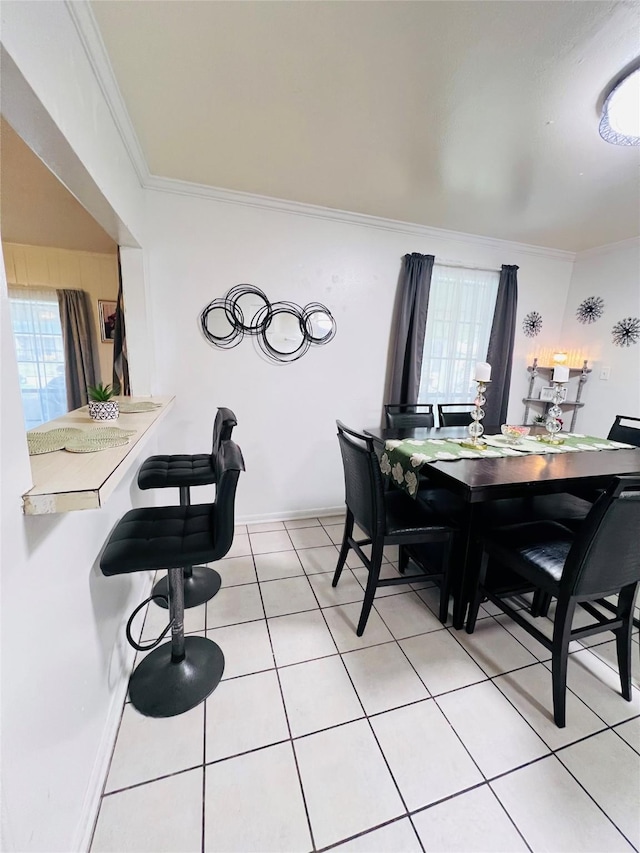 dining room with light tile patterned floors, baseboards, and ornamental molding