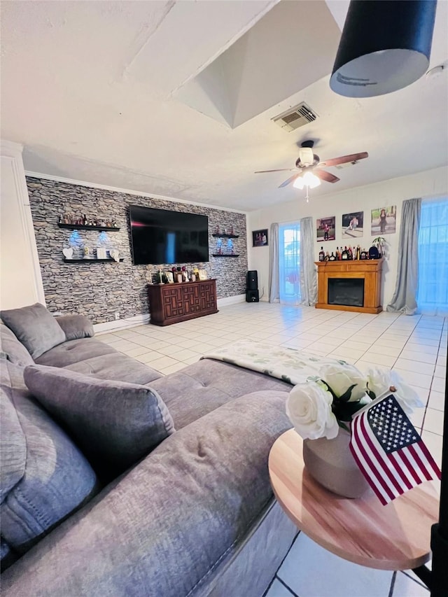 tiled living room with a fireplace, visible vents, and a ceiling fan