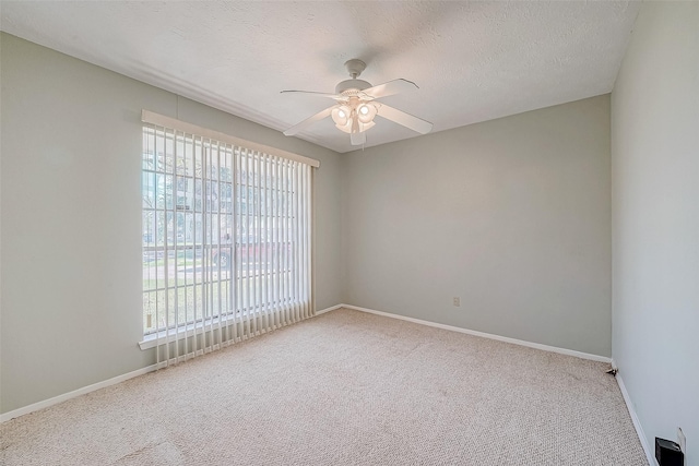 carpeted spare room with a ceiling fan, baseboards, and a textured ceiling